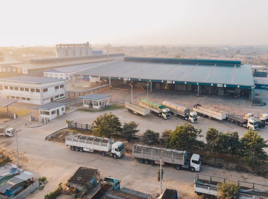 An aerial shot of factory trucks parked near the warehouse at daytime